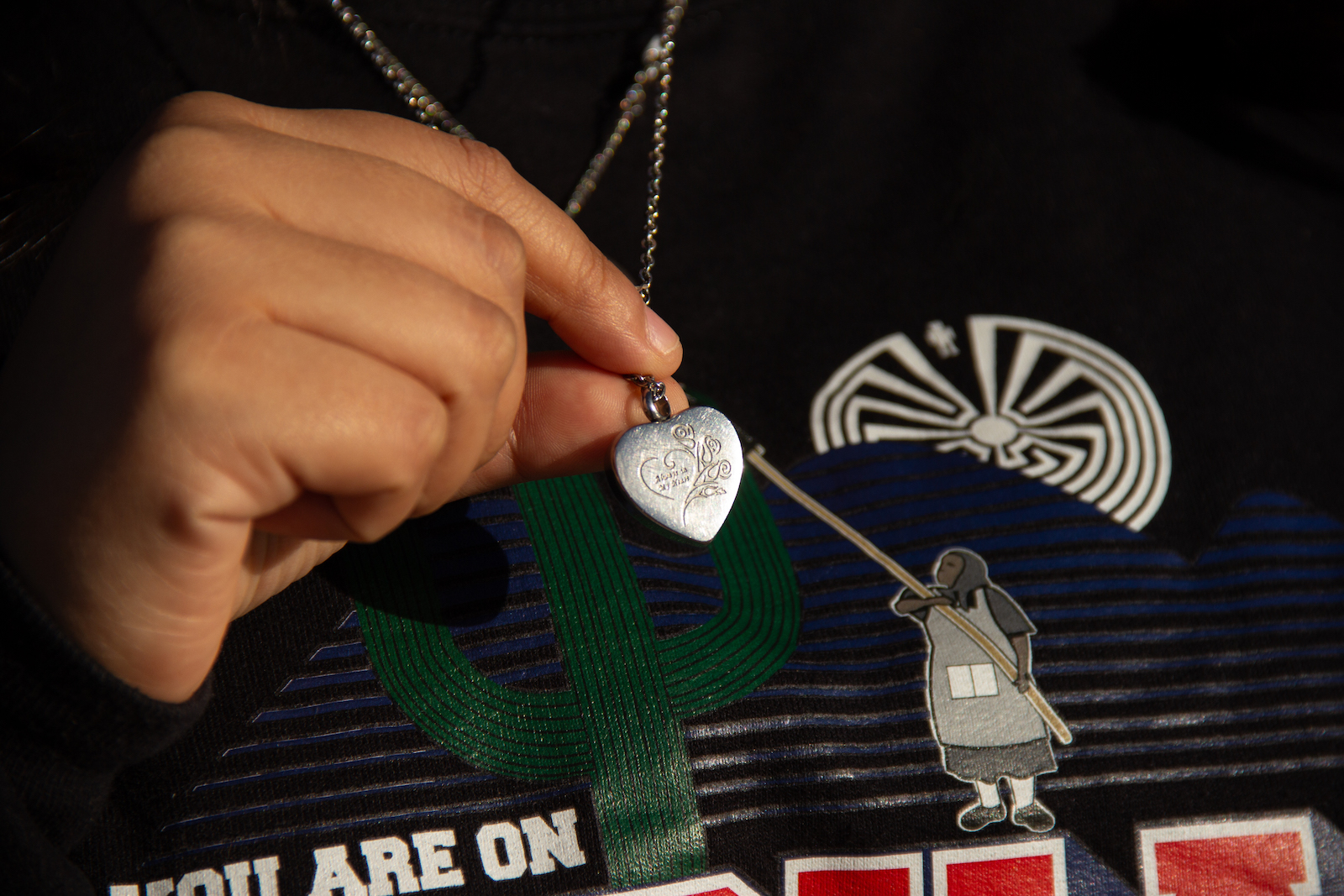 A hand holds a silver heart-shaped locket