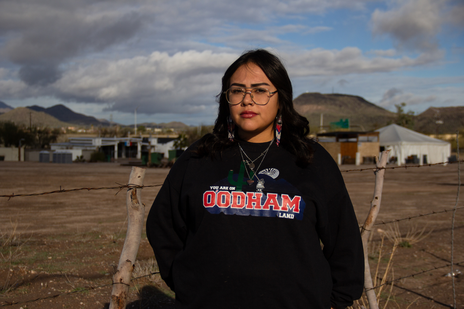 a woman in a black sweatshirt looks straight into the camera