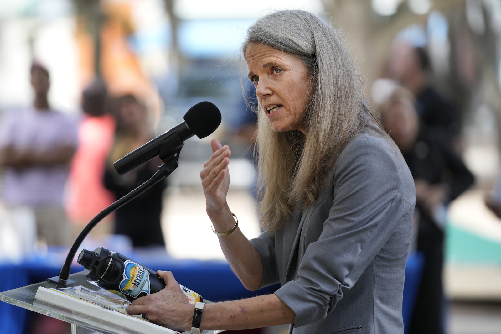 a woman stands at a podium with a microphone while talking