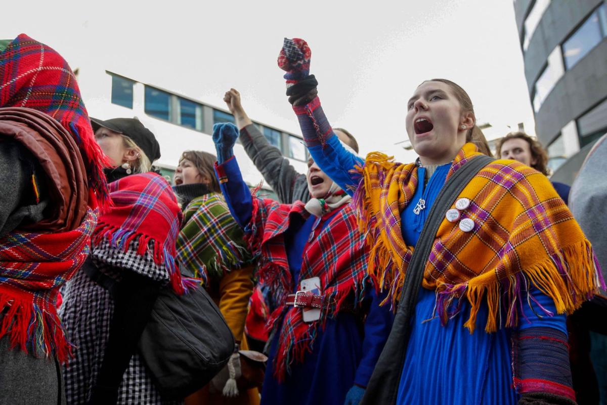 A group of people in Gaktis and with fists held high yell together as part of a chanting growd